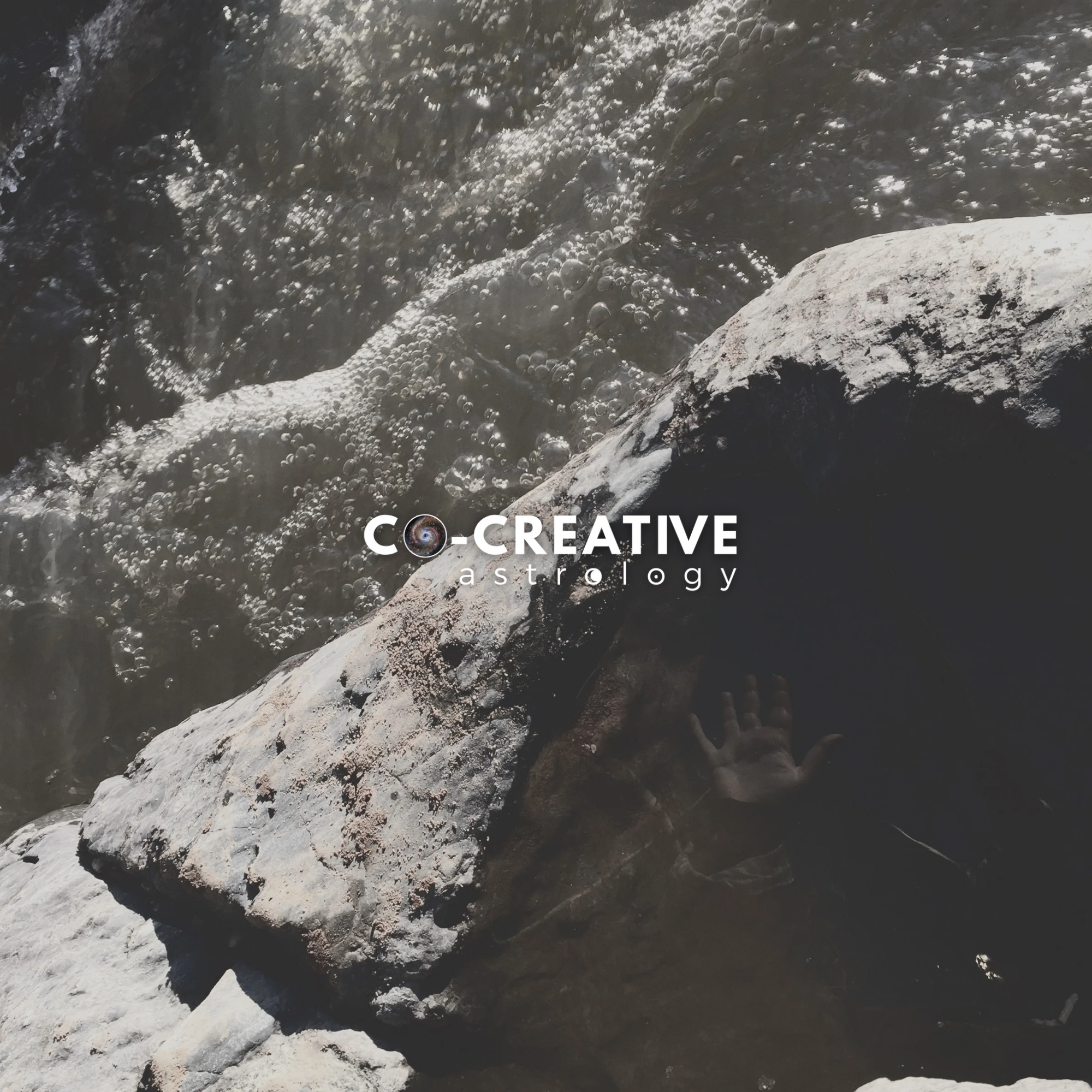 rushing river and stone with pool of still water and hand reflecting. text overlay reads co-creative astrology in center of the image over the stone and between the still and rushing water.